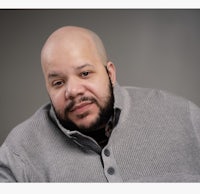 a bald man in a gray sweater is posing for a photo