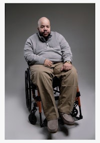 a man in a wheelchair sitting on a gray background