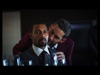 a man in a suit is kissing another man