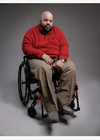 a man in a wheelchair sitting on a gray background