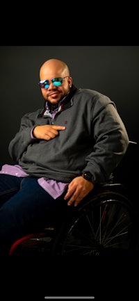 a bald man in a wheelchair wearing sunglasses