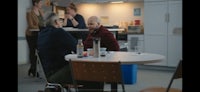 a group of people sitting around a table in a kitchen