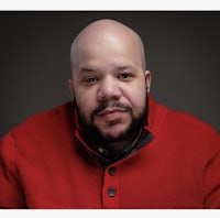 a bald man in a red sweater is posing for a photo